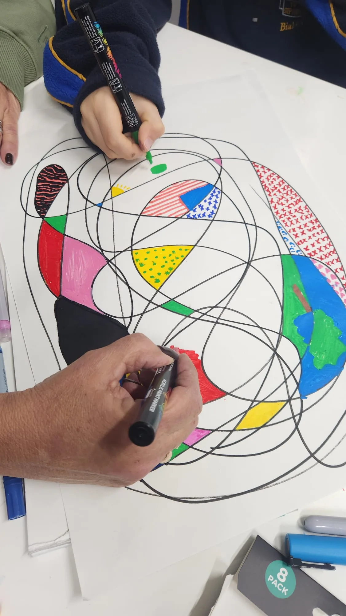Hands drawing together with coloured pencils at the Enso studio